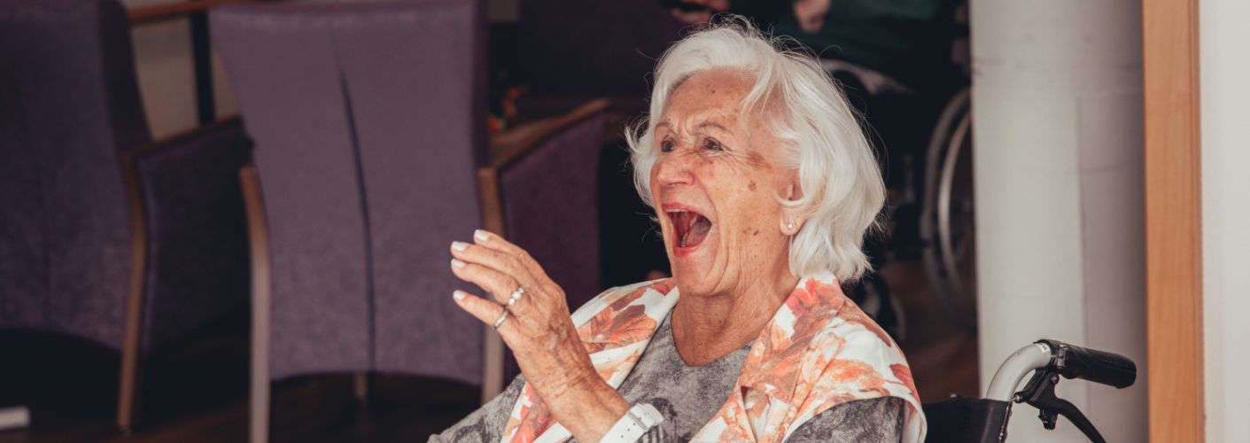 Alte Frau mit weißen Haaren lacht.